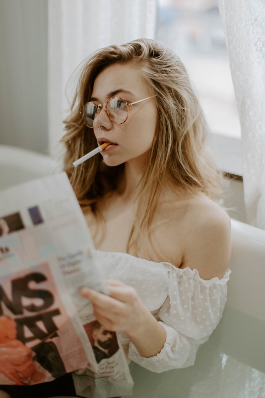 Chica con cigarrillo y leyendo revista